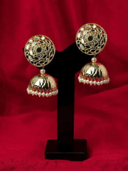 Gold and pearl jhumka earrings against a bold red background. The color contrast makes the product pop, grabbing attention instantly.