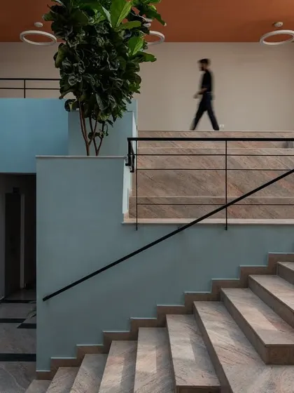 The interior of the Nirbhaya Centre is organized around a central, light-filled atrium with a grand staircase, designed to be an uplifting and non-intimidating space.