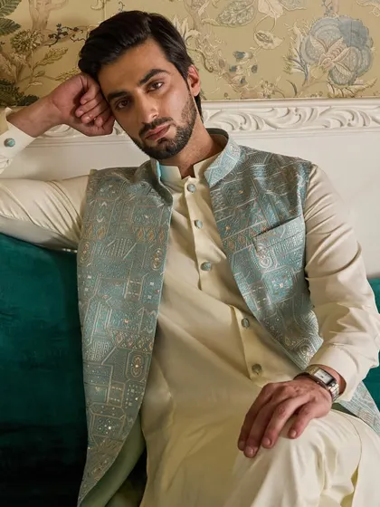 A close-up on the textured embroidery of the powder blue jacket. The mix of threads and sequins adds a subtle shimmer to the garment.