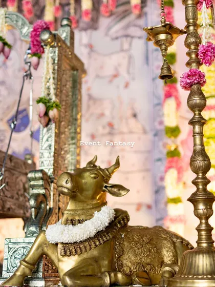A detail shot of a brass cow statue adorned with a jasmine garland. These small, thoughtful touches are essential for creating an authentic and blessed atmosphere for a naming ceremony.