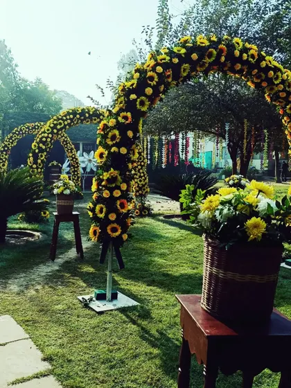 A grand entrance to a daytime event, marked by arches made of sunflowers, creating a sunny and welcoming pathway.