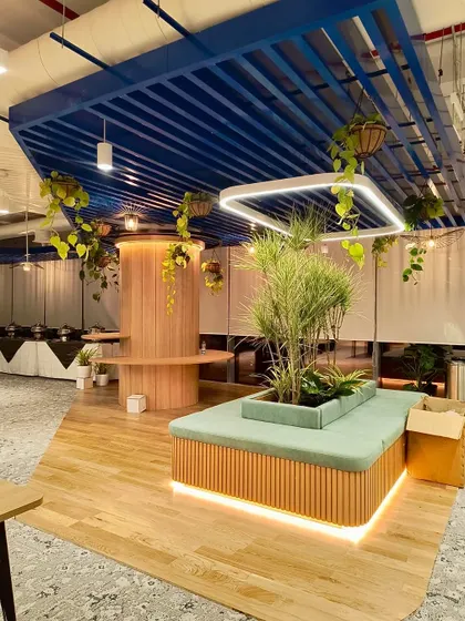 A wide view of the Bangalore project, showing how hanging plants and a large central planter with upholstered seating work together. This design creates a natural gathering spot within the office, promoting both relaxation and collaboration.