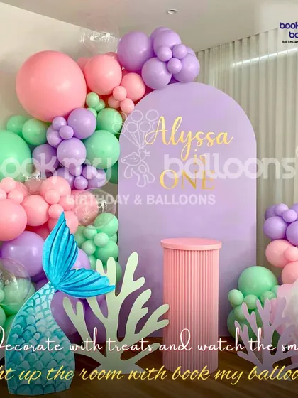 Alyssa's first birthday was a whimsical mermaid celebration. We used a soft pastel palette of lavender, pink, and mint green for the balloon decor, complete with a mermaid tail and coral props for a magical touch.