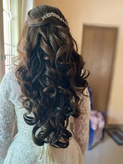 A classic half-up style with beautiful, bouncy curls, perfect for a Christian wedding gown. The look is completed with a simple, elegant tiara.