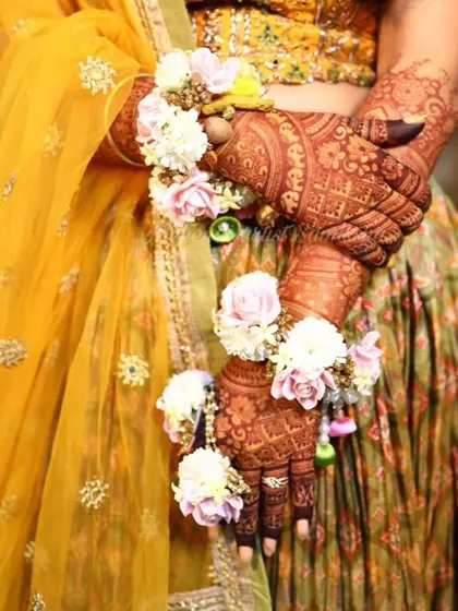 A beautiful shot of a bride's hands, adorned with floral jewelry. The details of the mehendi, the flowers, and the outfit all come together to create a stunning image.