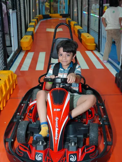 This young man is buckled in and ready to navigate the twists and turns of our exciting go-kart course.