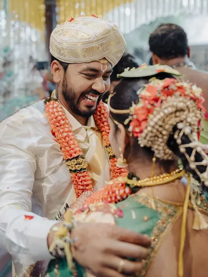 A groom’s happy, candid smile as he embraces his bride during the ceremony. This over the shoulder shot focuses on his genuine emotion, a fleeting moment of connection amidst the traditions.
