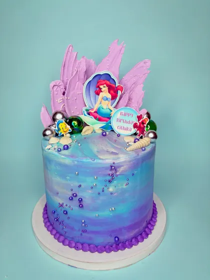 When I enjoy making a cake, it really shows. This Little Mermaid cake was so much fun to bring to life, with its purple and blue watercolor buttercream, chocolate shell details, and Ariel herself taking center stage.