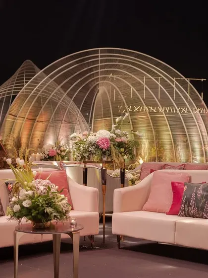 A cozy lounge nook at the musical reception, with plush pink sofas set against the backdrop of the grand, illuminated arched structures.