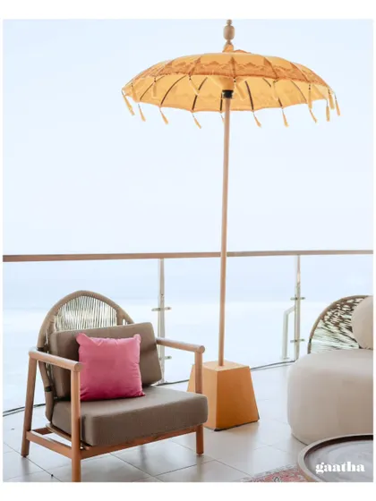 A serene seating spot with a view of the ocean, featuring a comfortable armchair and a yellow umbrella, perfect for guests to relax.