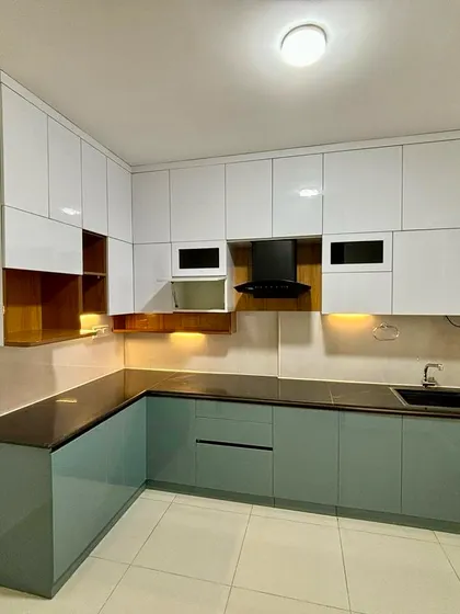 A finished L-shaped kitchen with glossy white upper cabinets and muted green lower cabinets, creating a fresh and contemporary feel.