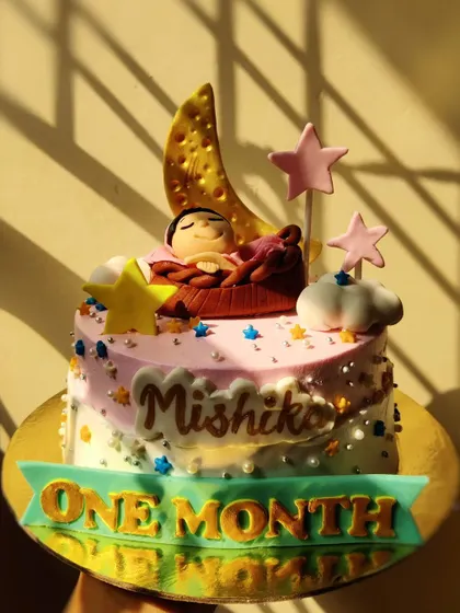 Celebrating baby Mishika's very first month! This sweet cake features a tiny baby sleeping on a crescent moon, surrounded by stars. First milestones are always so special.