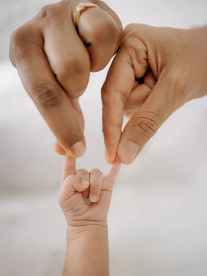 A creative pose with parents' hands forming a frame around their baby's tiny hand, symbolizing protection and love.