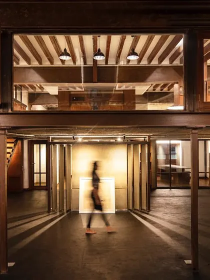 An atmospheric shot of the 'Tianu Revival Project.' The design plays with light and shadow, using a double-height space and a mezzanine level to create a dramatic and layered retail experience that feels both historic and contemporary.