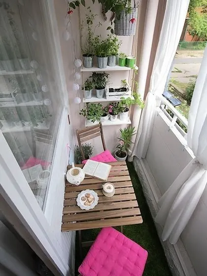 A bright and charming balcony makeover idea, featuring a small bistro set, wall-mounted shelves for plants, and cheerful pink cushions to add a pop of color.