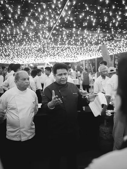 A black and white photo of me briefing my team under the warm glow of event lighting.