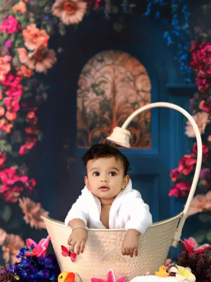 A baby enjoys a luxurious bath in a vintage-style tub, surrounded by a beautiful floral archway.