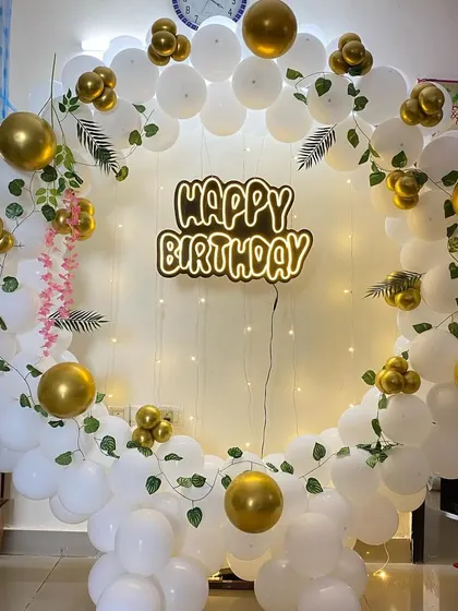 A clearer view of the white and gold birthday balloon ring with vine accents.
