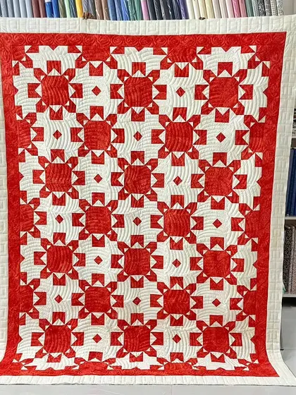 A gorgeous red and white quilt with an intricate star and lattice pattern.