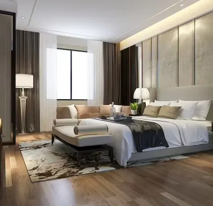 A hotel-inspired luxury bedroom with a wood-panelled floor, a plush upholstered headboard, and a comfortable seating area, designed for ultimate comfort.