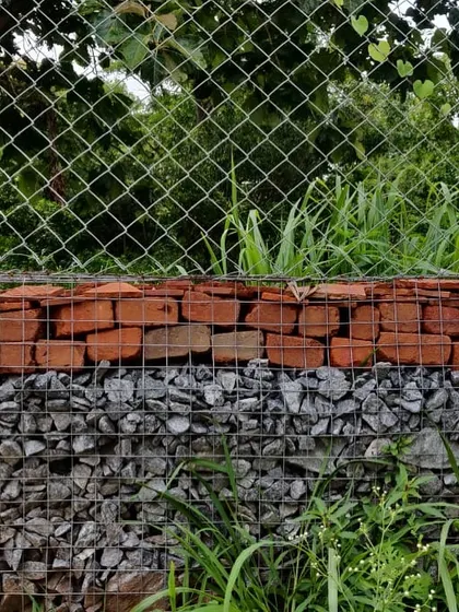 A close-up of the gabion wall, showing the different materials used as fill. We use waste stone and broken bricks from the site, making it a cost-effective and circular building method.