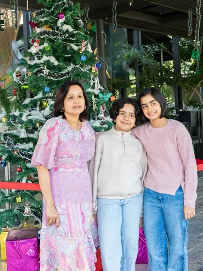A mother and her children posing in front of our Christmas tree during the festive season.