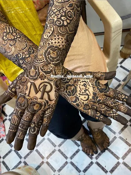 A beautiful design with the initials 'N' and 'R' on one palm and a name in Arabic on the other.