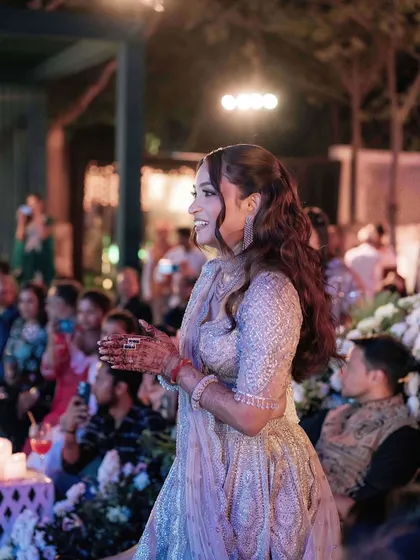 A candid moment of joy from a sangeet night. The makeup is designed to look great even in action, with a soft glam that enhances her features as she enjoys the celebration.