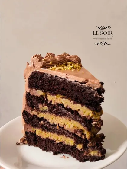 A slice of my viral Pistachio Kunafa Chocolate Cake. This special treat, made only for bakesales, has layers of chocolate cake and crunchy pistachio kunafa filling.
