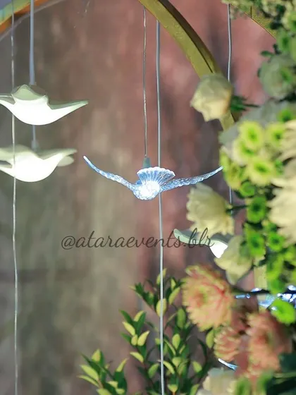A close-up of hanging bird decorations at a floral-themed baby shower. These delicate, illuminated birds add a touch of whimsy and magic to the overall decor.