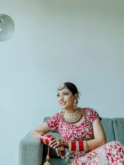 A relaxed portrait of the bride sitting on a couch. This shot captures a moment of calm and happiness before the wedding festivities.