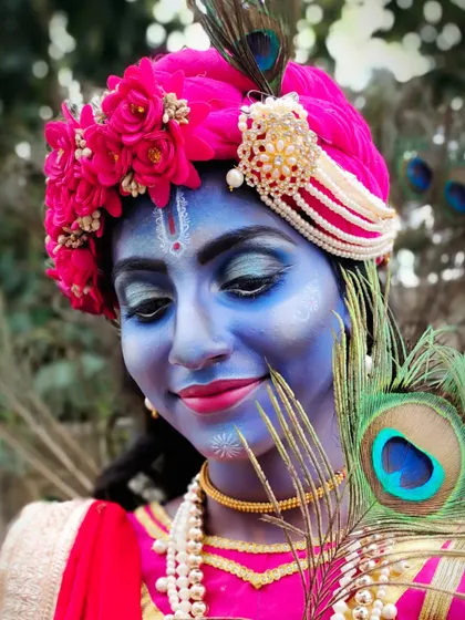 A close-up of the Krishna character makeup, focusing on the detailed face painting, the 'tilak', and the peacock feather, which are all symbolic elements.