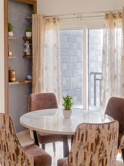 The cozy dining corner in the Chennai home, with a round marble-top table and comfortable upholstered chairs, is perfect for intimate family meals.