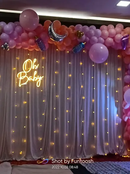 A closer look at the 'Oh Baby' balloon arch decoration, showing the mix of pastel colors and metallic accents.