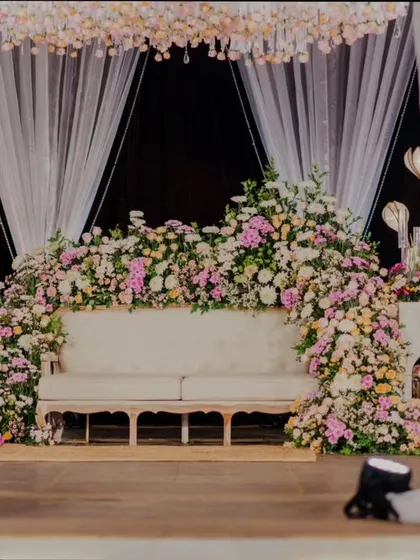 The reception stage, with a comfortable sofa nestled in a sea of pink and white flowers.