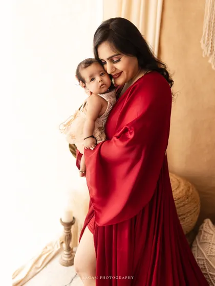 A mother's loving embrace. This lifestyle portrait captures a tender moment between a mom and her baby in a warm, naturally lit studio.