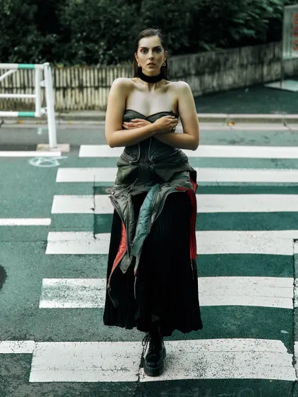 A powerful, stationary pose in the middle of a Tokyo crosswalk. The symmetry of the lines on the road draws the eye directly to the model.