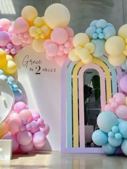 A beautiful pastel rainbow balloon arch with a large light-up number '2', creating a soft and dreamy atmosphere.