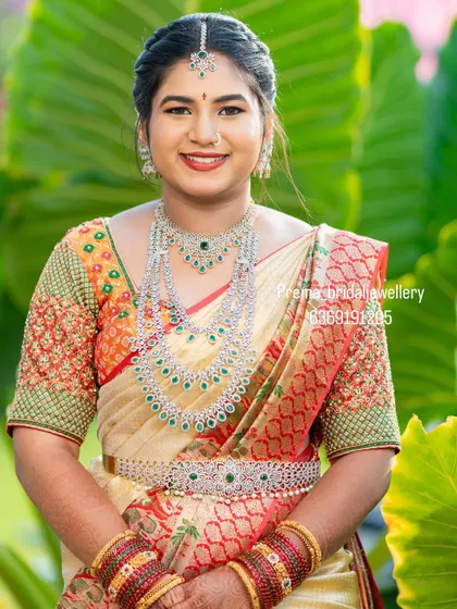 Bride Neelima looks absolutely radiant in this grand AD and emerald stone bridal set. It includes a choker, a long layered necklace, and a matching vaddanam.