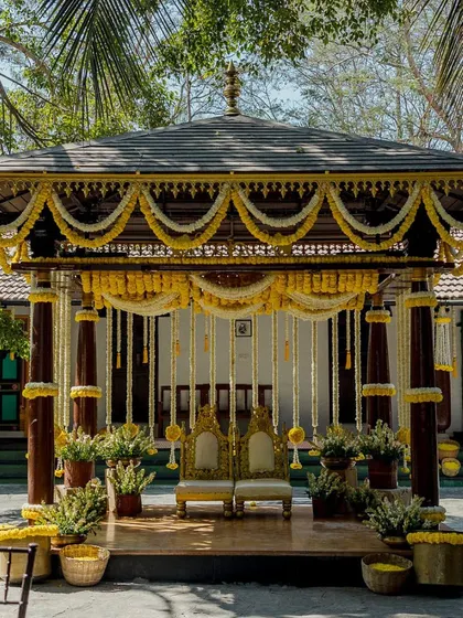 A direct view of the Haldi mandap, showcasing the regal golden chairs for the couple and the beautiful floral arrangements that frame the stage. The design is both traditional and joyful.