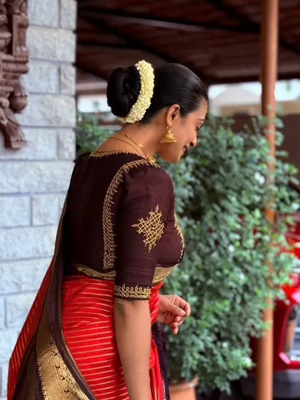 Another view of the elegant brown blouse, showing the delicate embroidery detail on the back and sleeve.