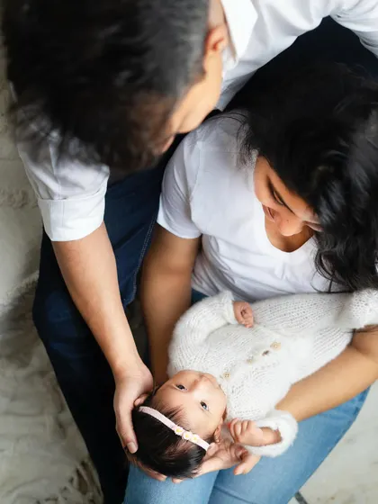 An overhead perspective of the family admiring their baby. This angle provides a unique and intimate view of their loving interaction.