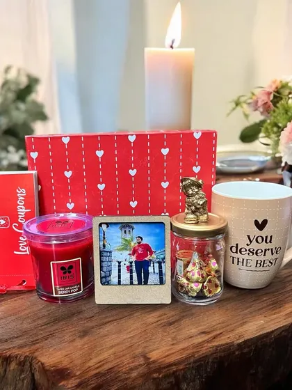 A romantic and cozy gift set for him. This Valentine's hamper includes "Love Coupons," a scented candle, a "You Deserve the Best" mug, a mini photo frame, and a jar of Hershey's Kisses.