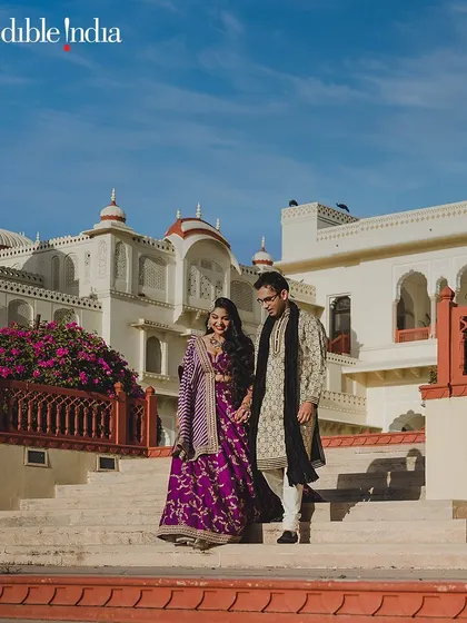 A couple walks down the steps of a palace in Jaipur, a classic and happy pre-wedding shot.