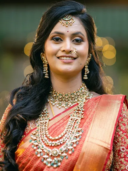 A close-up of our bride Manasa. This shot highlights her smile and the detailed neckline of her custom red bridal blouse.
