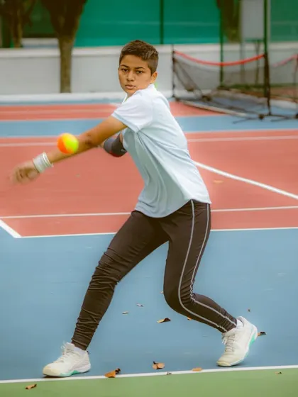 This young player is captured mid-swing, demonstrating the follow-through we teach in our orange ball program. Proper technique is instilled from the very beginning to create a solid foundation for future growth.