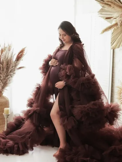 A quiet moment of reflection. This side profile shot beautifully showcases the baby bump, with the soft light and flowing gown adding a touch of grace and elegance.