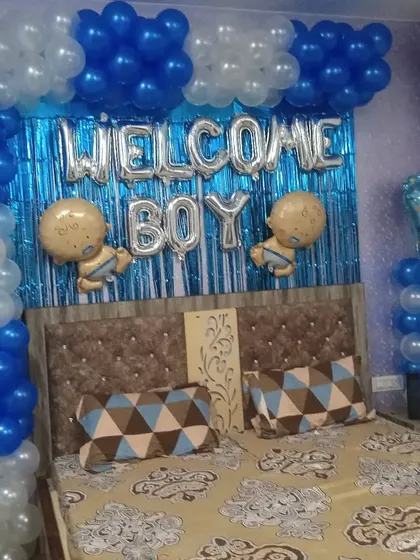 A "Welcome Boy" bedroom decoration. I used a blue shimmer curtain as a backdrop, silver foil balloons, and a blue and white balloon frame to create a festive look for the new arrival.