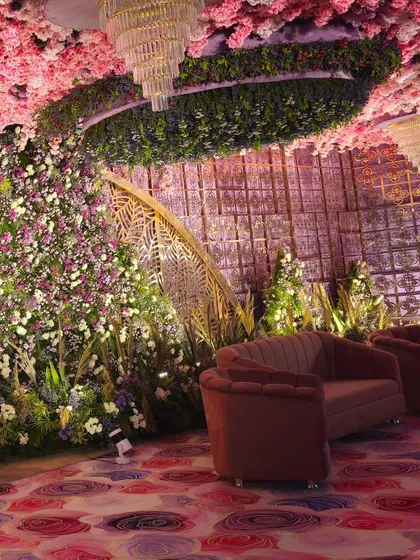 A luxurious lounge area for guests, featuring a ceiling covered in pink blossoms and greenery. The intricate wall panels and plush seating create a sophisticated and comfortable space.