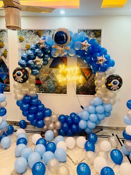 A closer view of the home-based space theme, showing the details of the astronaut-themed foil balloons and the neon "Happy Birthday" sign.